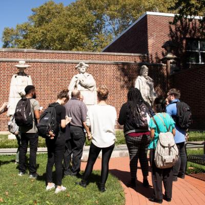 students and educators in front of statues